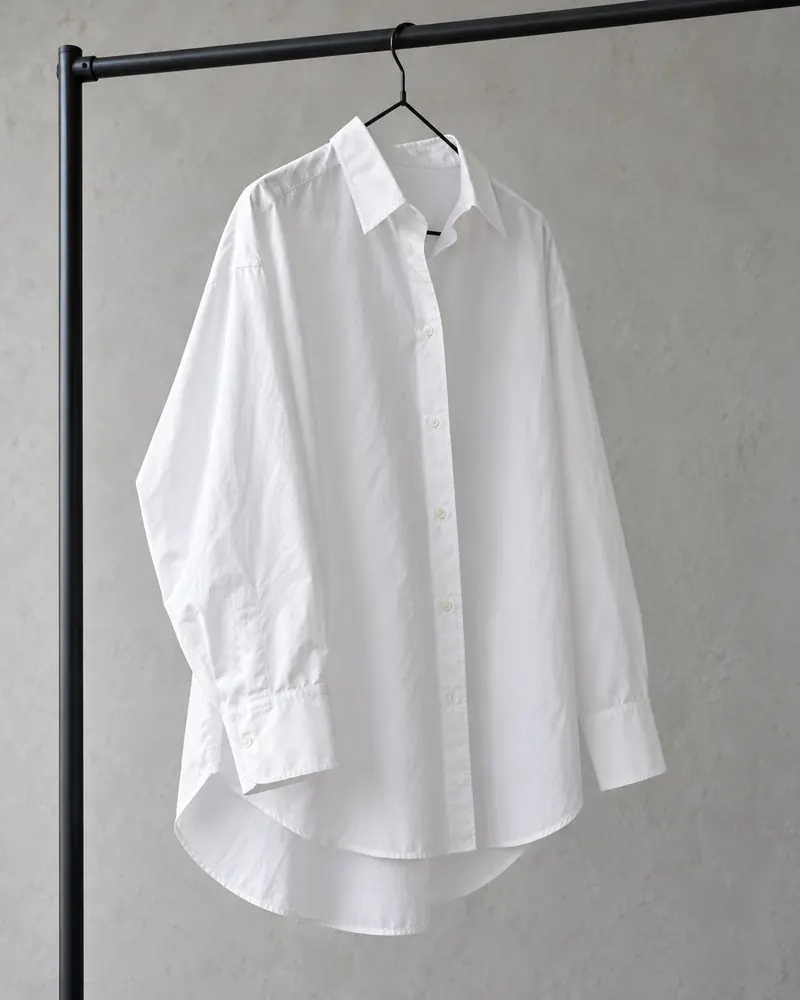 Camicia oversize bianca in popeline appesa a una stender nera